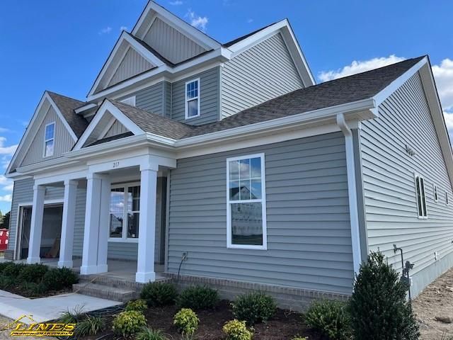 Blue two-story house with white trim, pillars, and a gray roof on a sunny day.