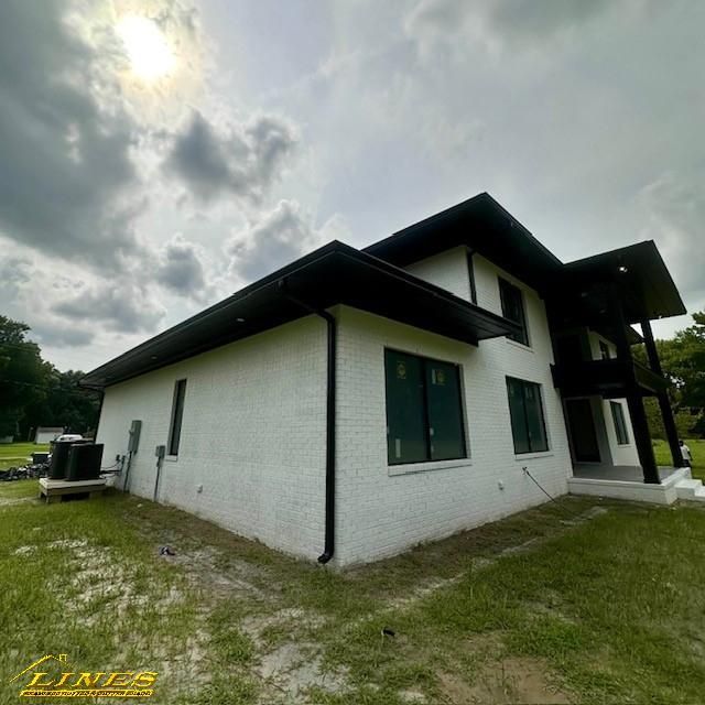 Modern two-story white brick house with black trim under a cloudy sky.