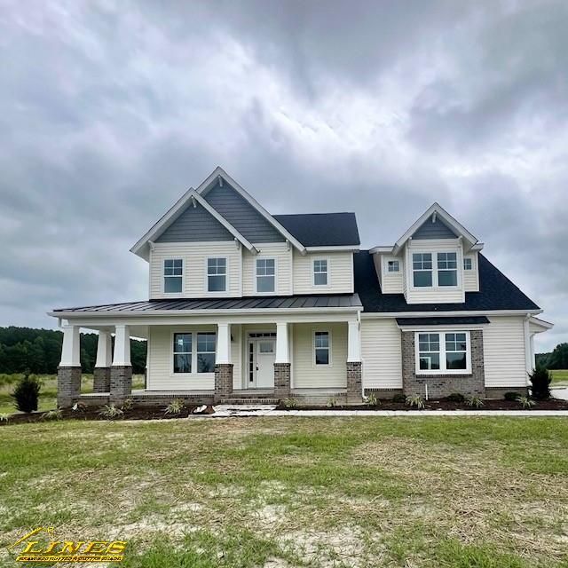 Two-story beige house with gray roof and accents, front porch, and a cloudy sky.