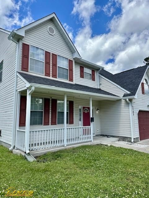 Two-story beige house with red shutters and door, a covered porch, and green lawn under a cloudy sky.