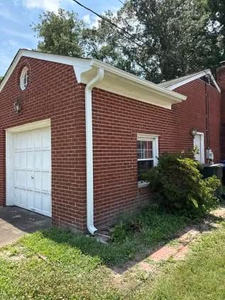 Red brick garage with white door, window, and trim; green grass.
