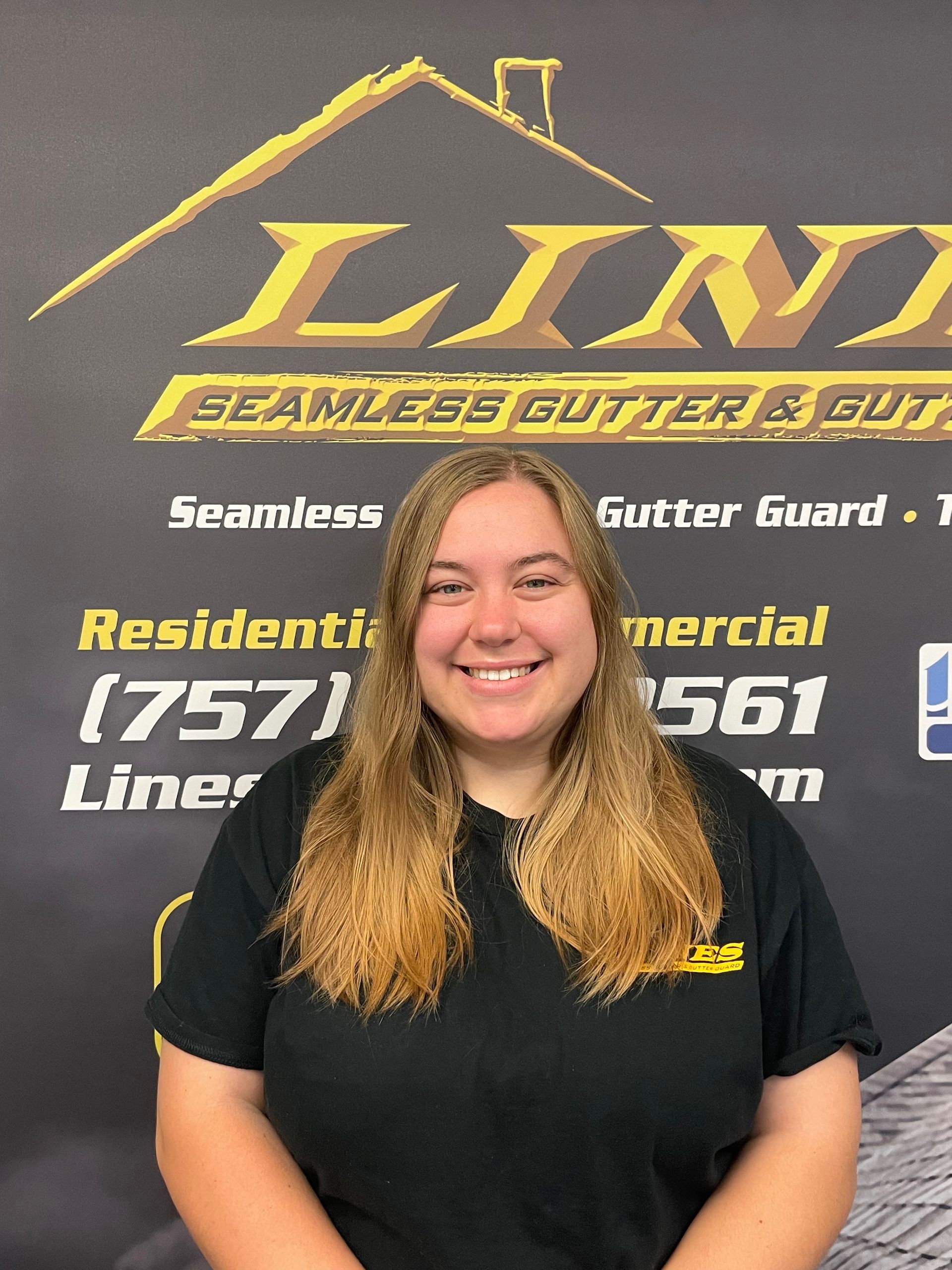Woman with long blonde hair smiles in front of a company logo for a seamless gutter business.