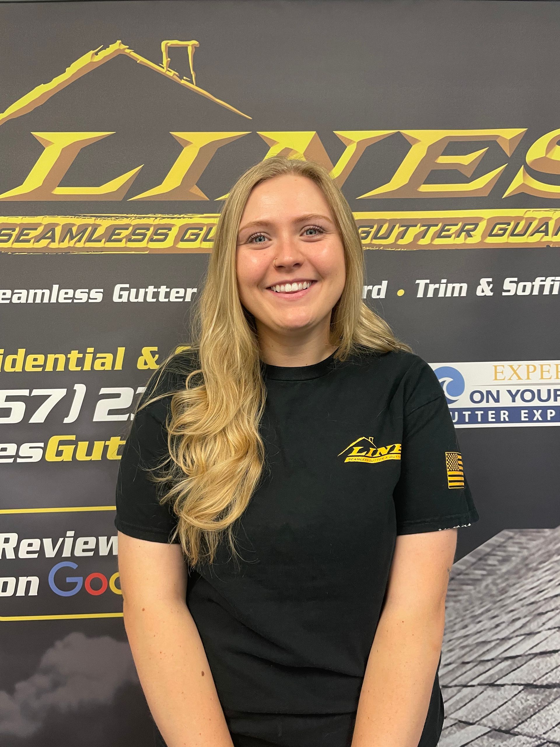 A woman with blonde hair in a black shirt smiling in front of a business logo.