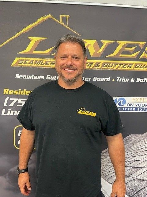 Man in black shirt stands in front of a banner for a gutter company.