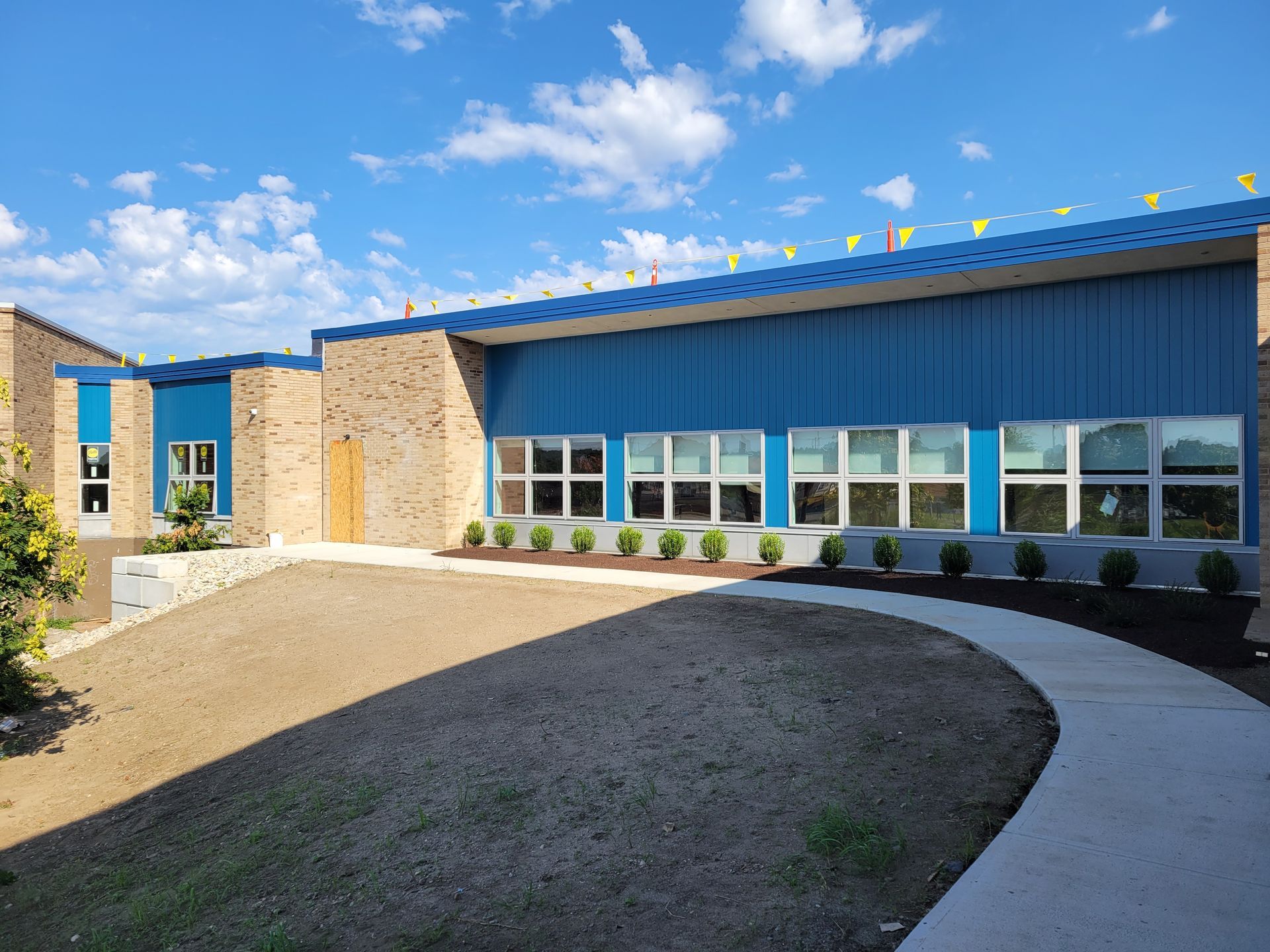 A large blue building with a lot of windows and a walkway leading to it.