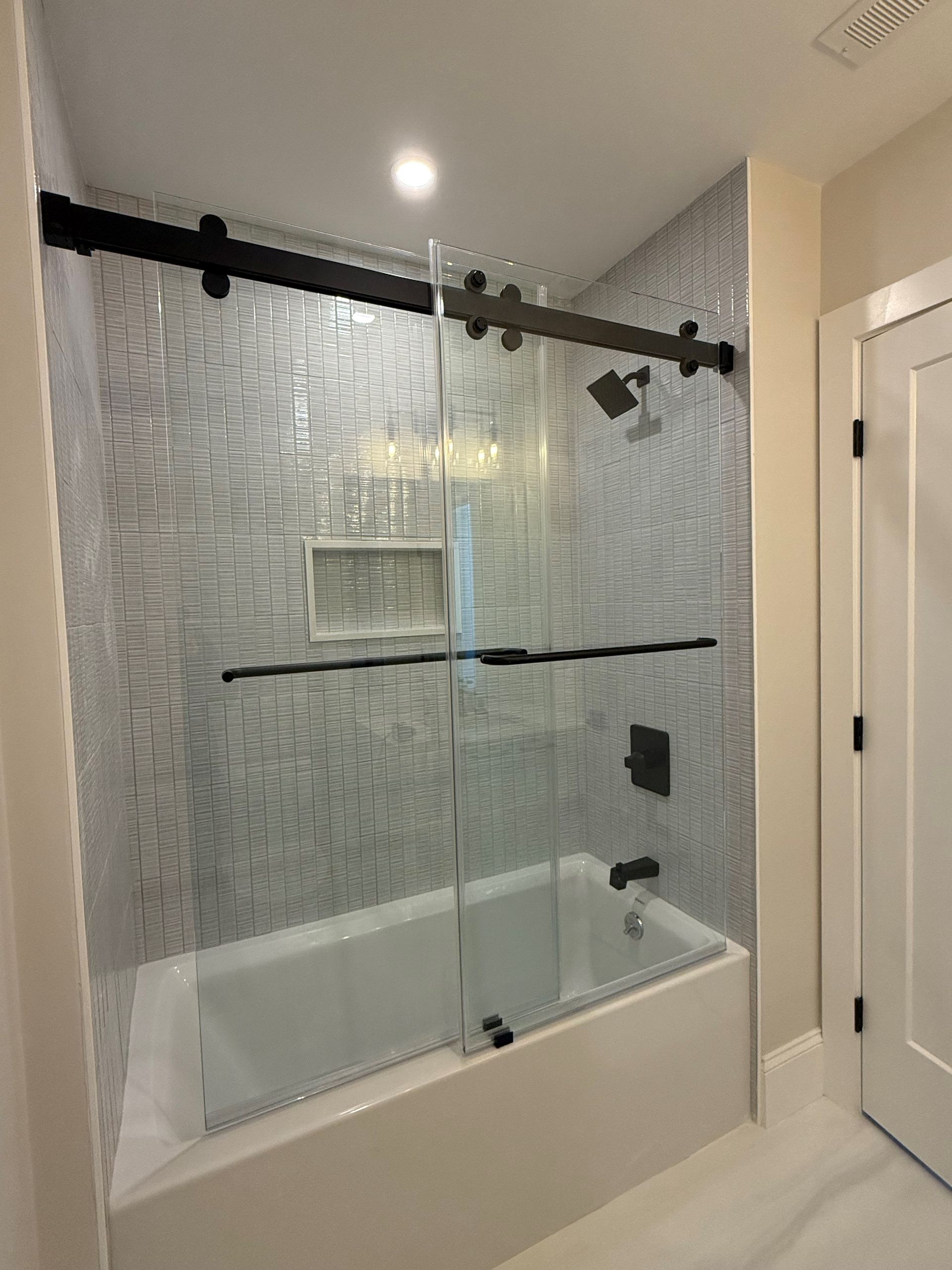 A bathroom with a bathtub and a sliding glass shower door.