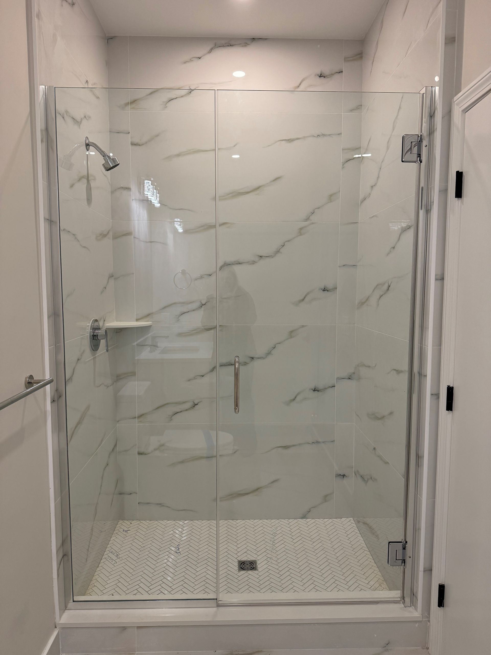 A bathroom with a walk in shower with a glass door.