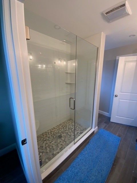 A bathroom with a walk in shower and a blue rug