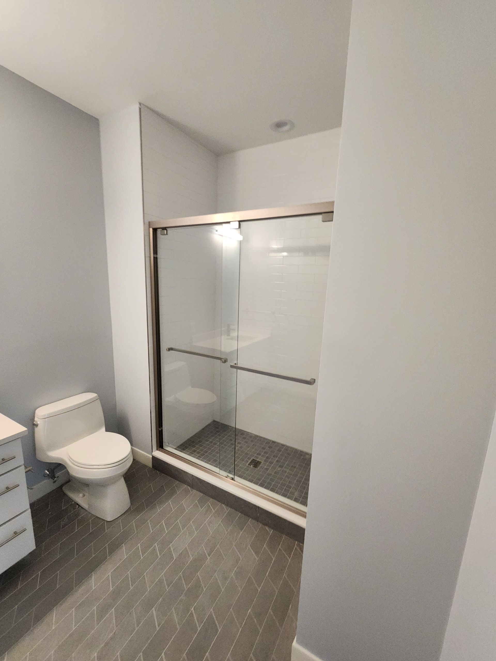 A bathroom with a toilet , shower and sink.