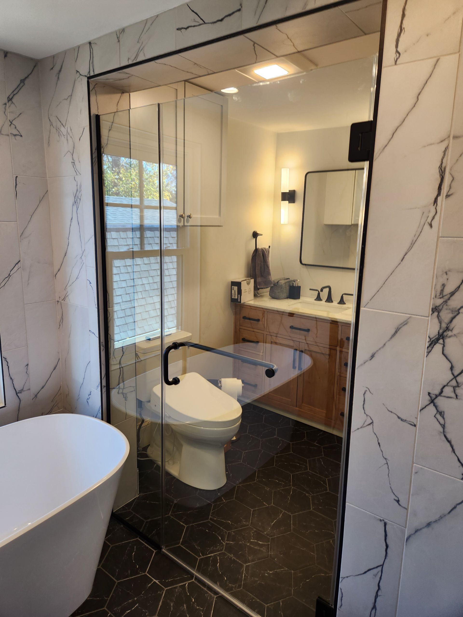 A bathroom with marble walls and a glass shower door