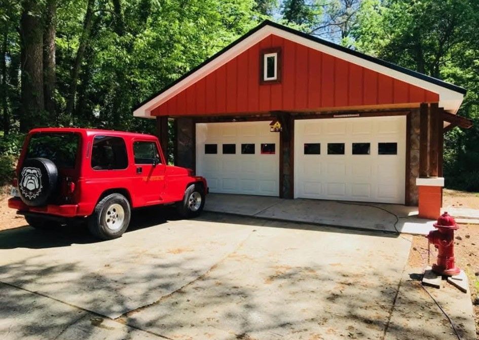 Red Jeep parked in front of a red two-car garage with white doors and a fire hydrant.