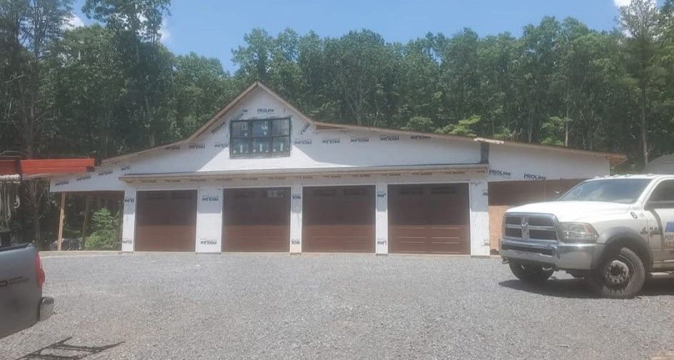 Garage under construction with four doors, white truck parked in front.