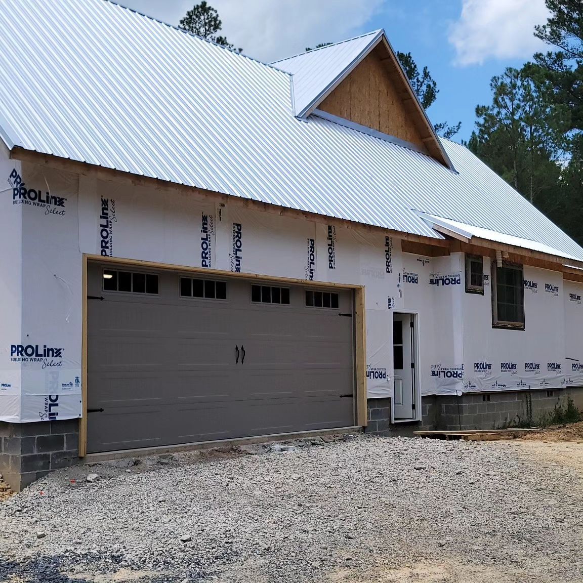 New construction house with a gray garage door and metal roof.
