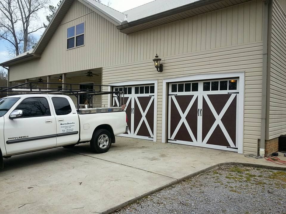 White pickup truck parked in front of a house with two brown and white garage doors.