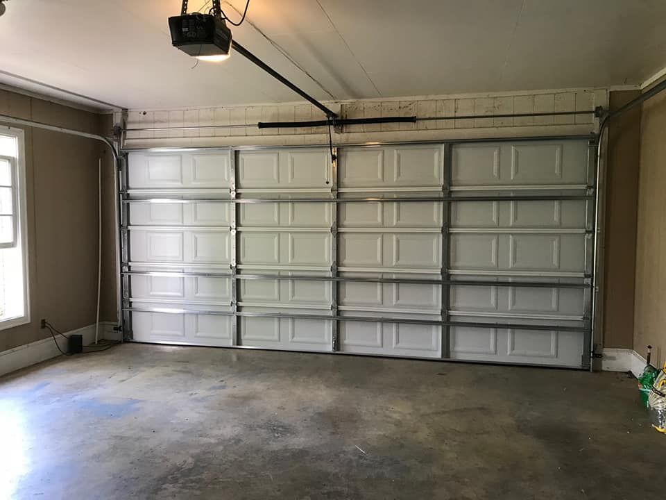 Empty garage with closed white panel door and concrete floor.