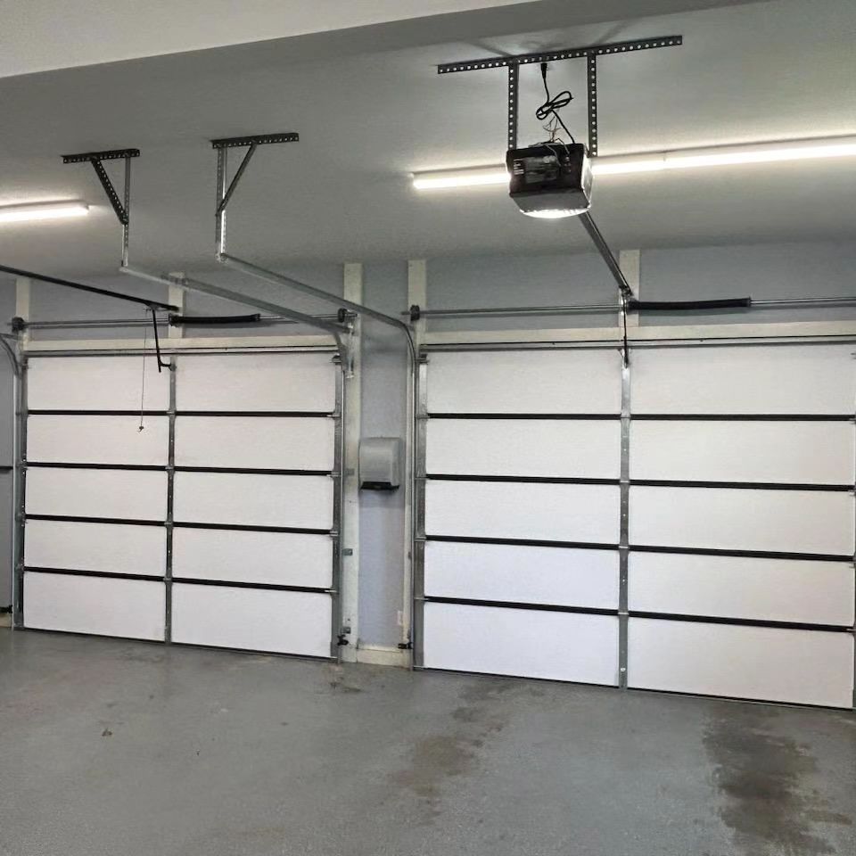 Two white garage doors with black trim in a garage.
