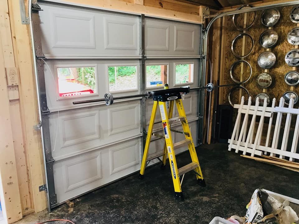 Garage door partially open, step ladder beneath. Inside the garage, some decorations on the wall.
