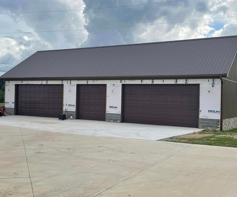Brown garage doors on a building with a brown metal roof and a concrete driveway.