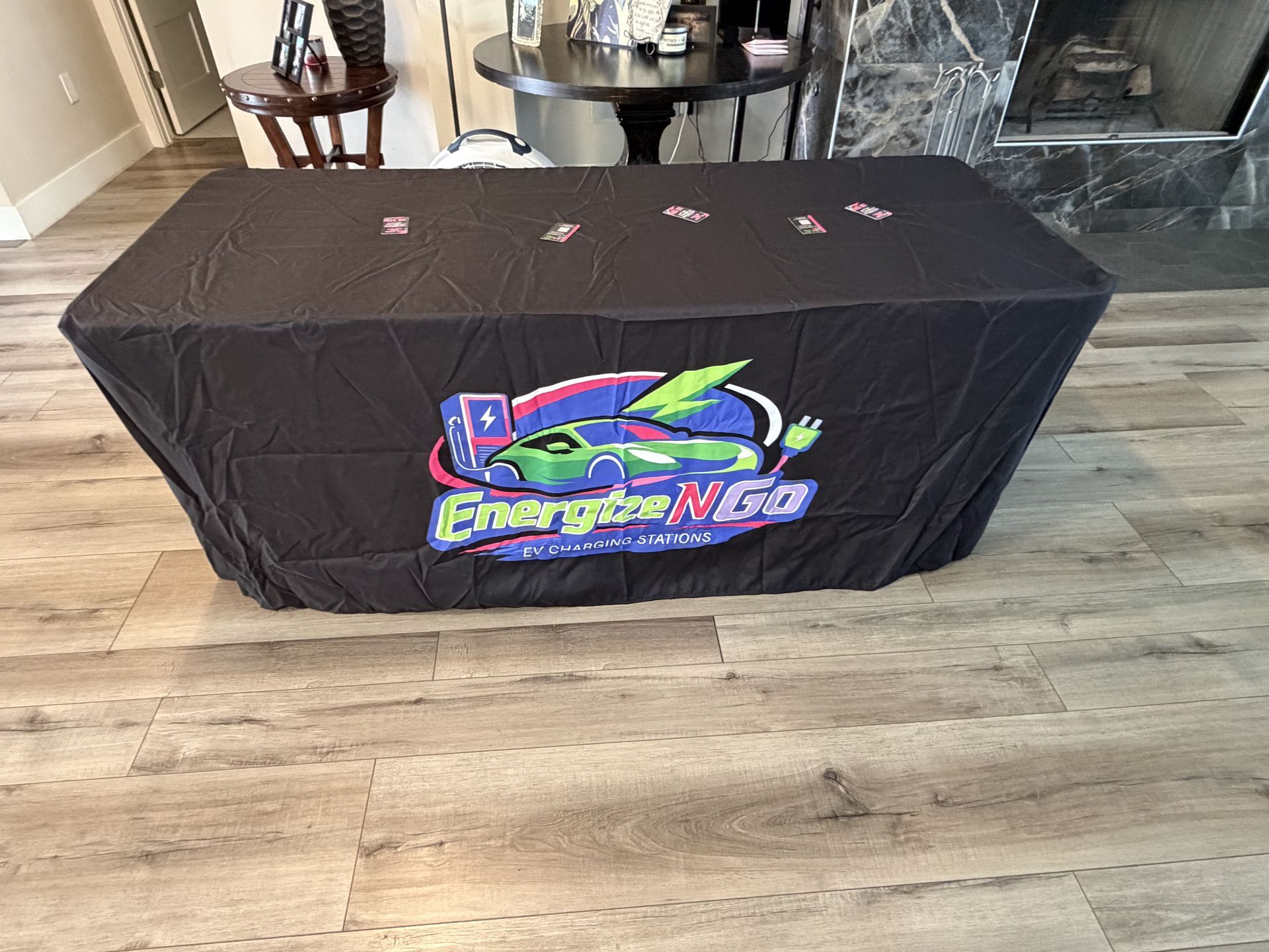 Black table with EnergyNet logo draped in a living room on a wood floor.