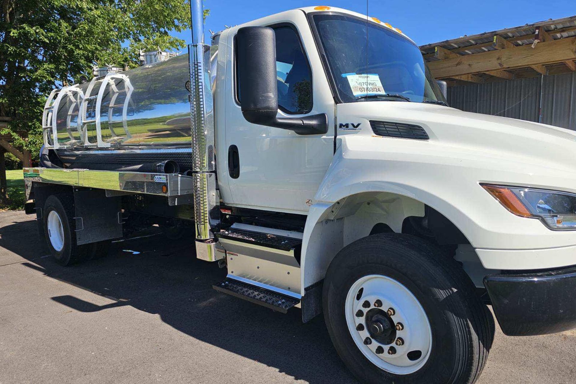 White septic tank truck with a red tank parked on grass.