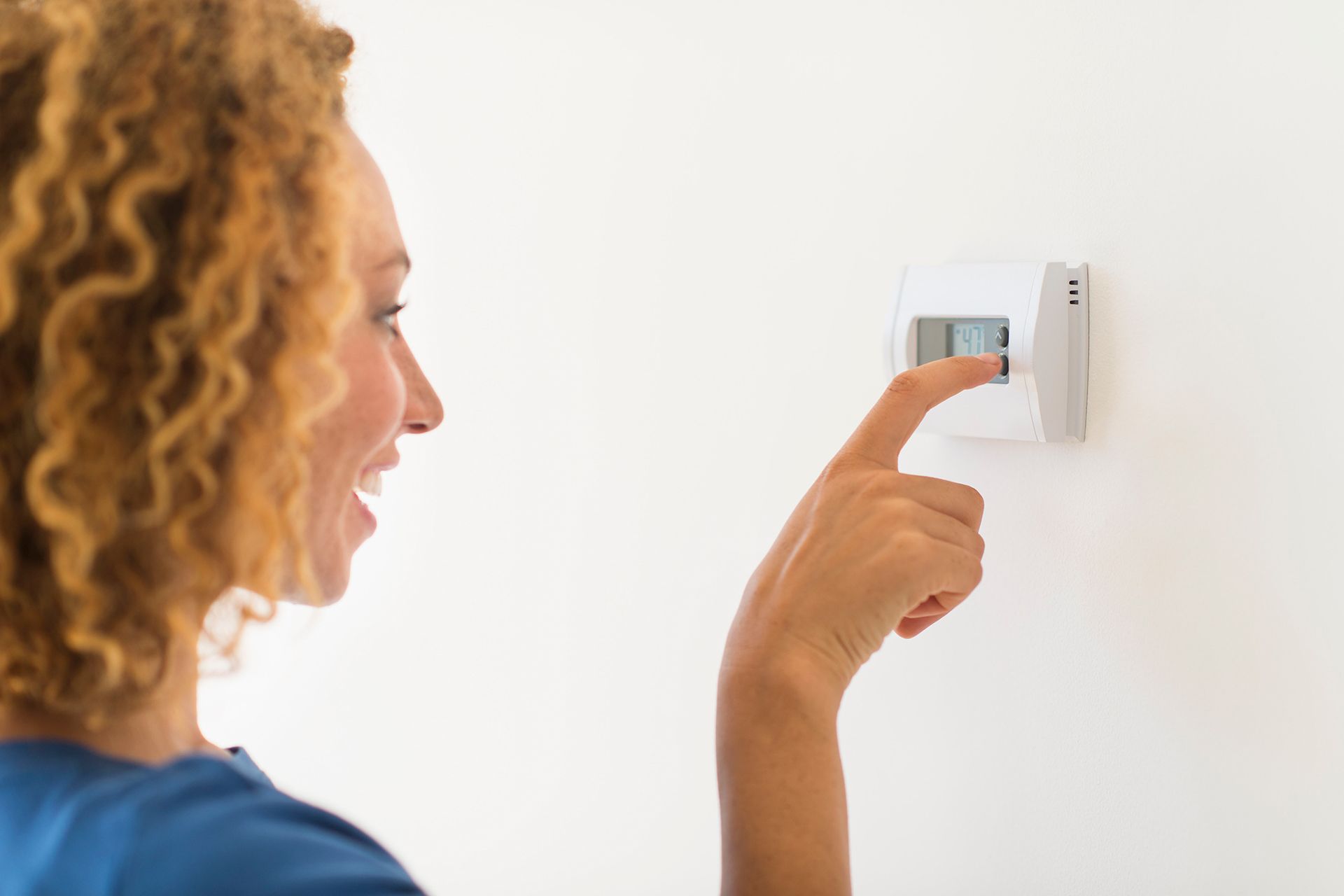 Woman using digital thermostat