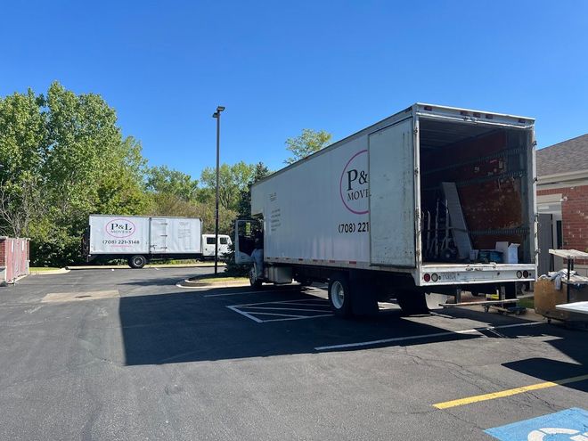 Two white box trucks parked in an empty lot on a sunny day