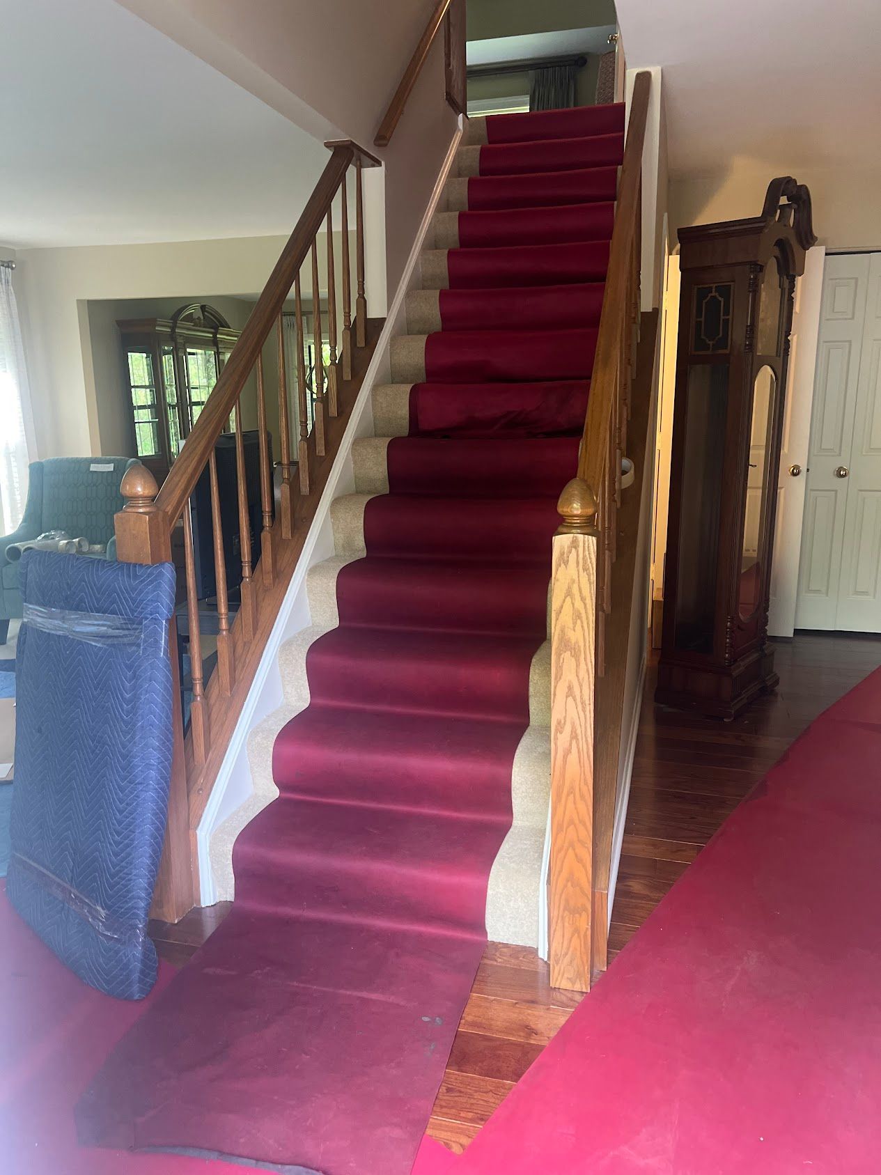 Carpeted staircase with a red runner in a home hallway, beside a wooden banister and antique mirror.