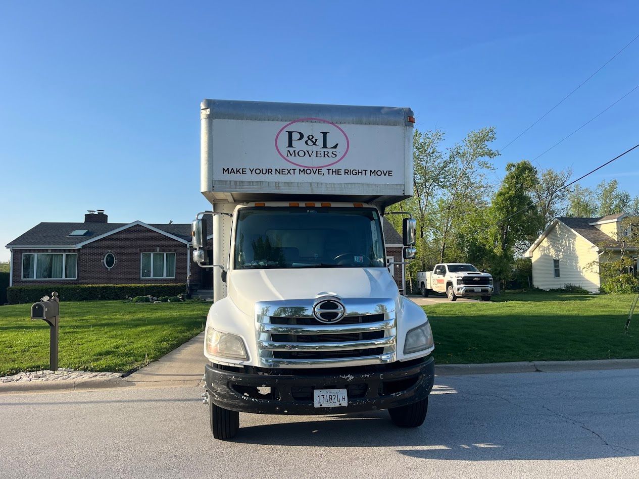 White box truck with P&L logo parked on a residential street in front of houses.