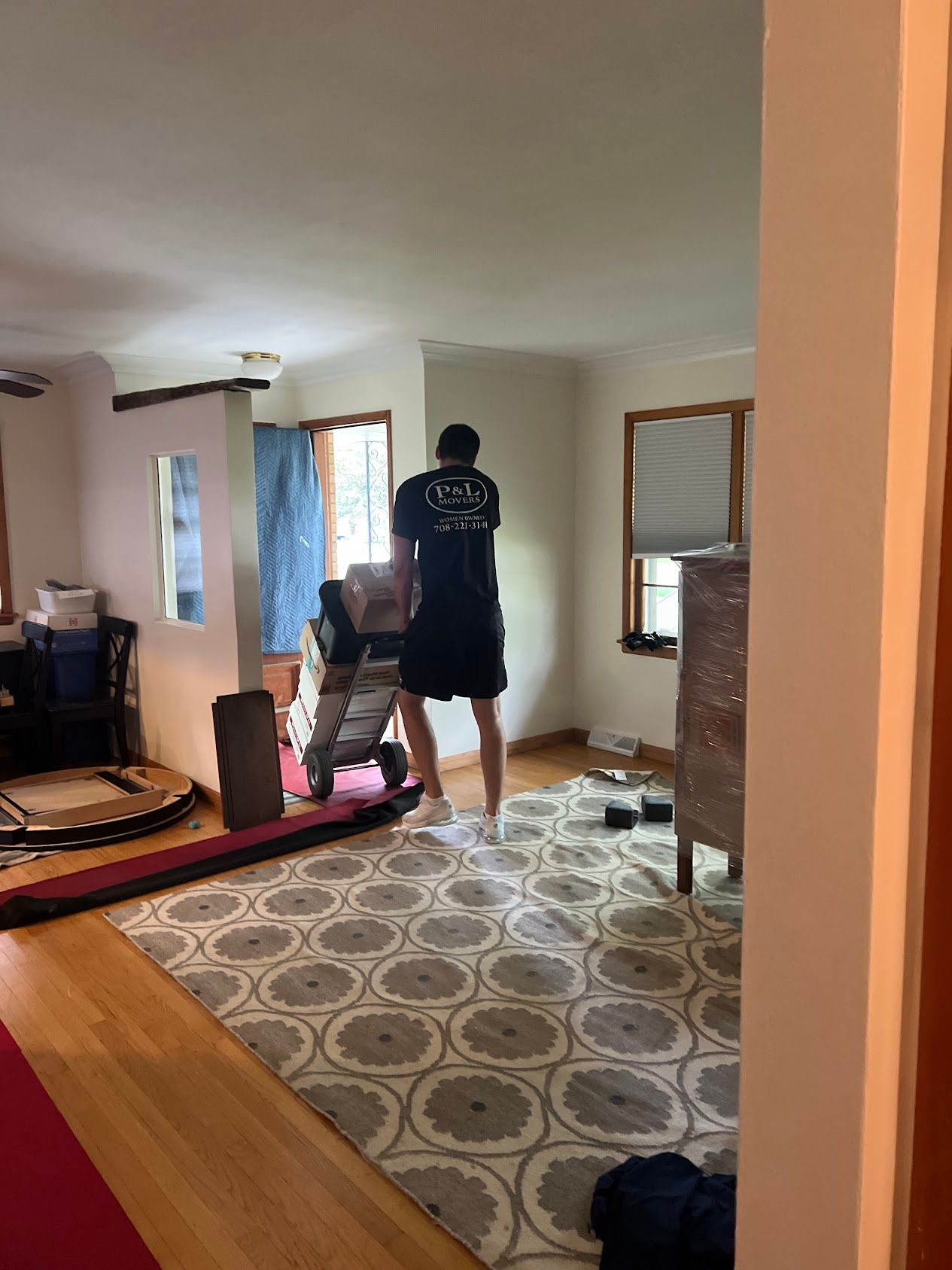 Person standing in a living room beside a pink yoga mat and chair, with patterned rug and windows.