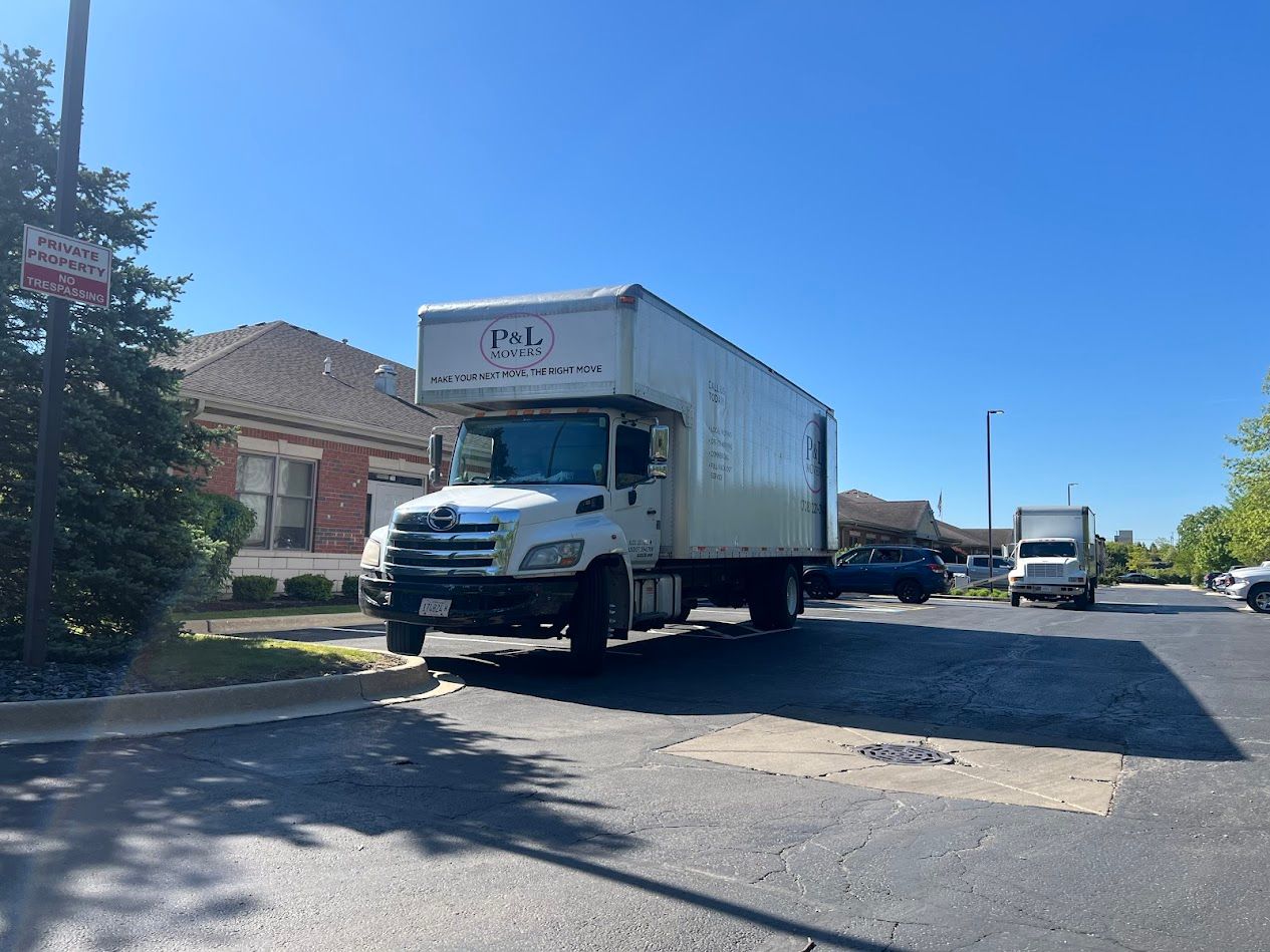 White box truck parked on a sunny street beside houses and another truck in the distance