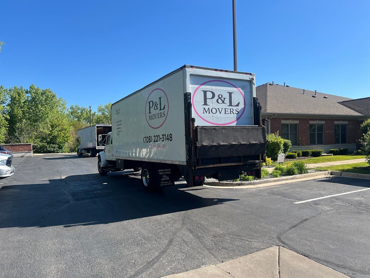 P&L Moving truck parked in a sunny apartment lot beside a brick building