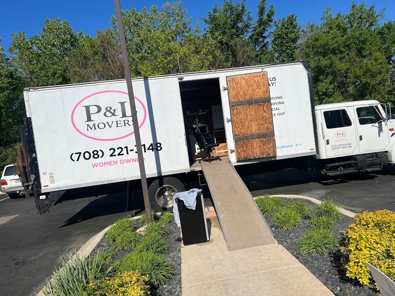 P&I Movers truck parked with rear ramp lowered beside a walkway and landscaped area