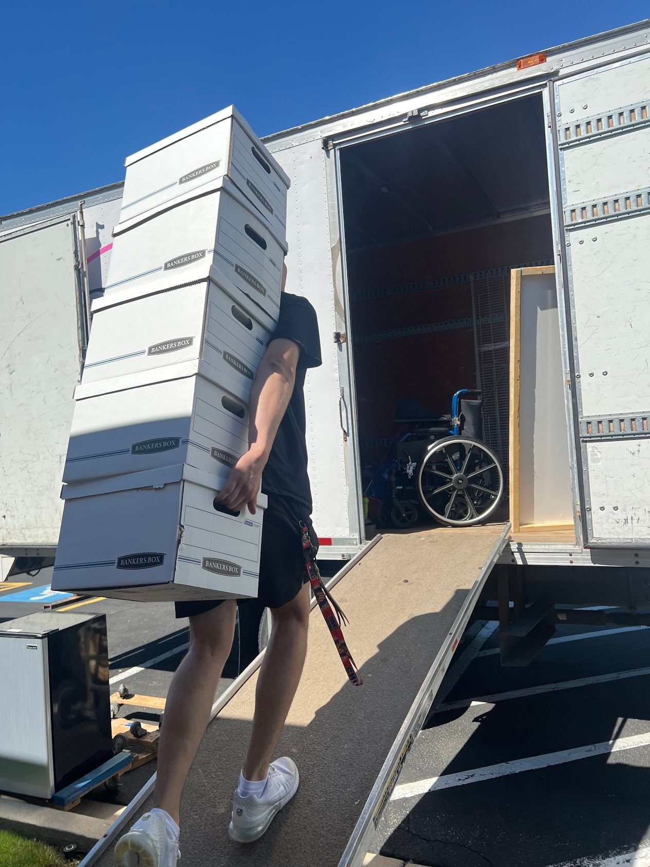 Person carrying stacked boxes up a ramp into a moving truck outdoors