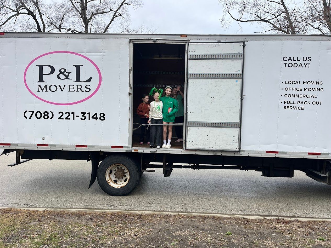 P&L Movers box truck parked roadside with two people standing in the open cargo door