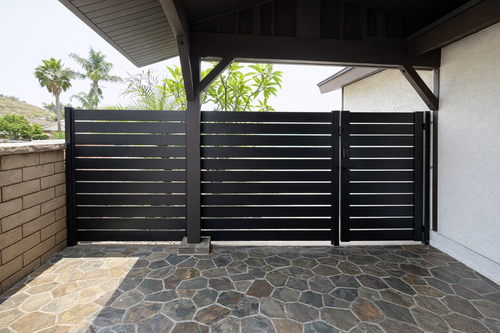 Covered patio with a black slatted fence and stone floor