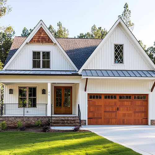 White farmhouse with brown accents and a wooden garage door.