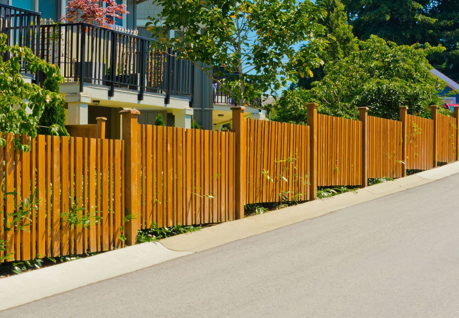Wooden fence bordering a residential property along a paved road.