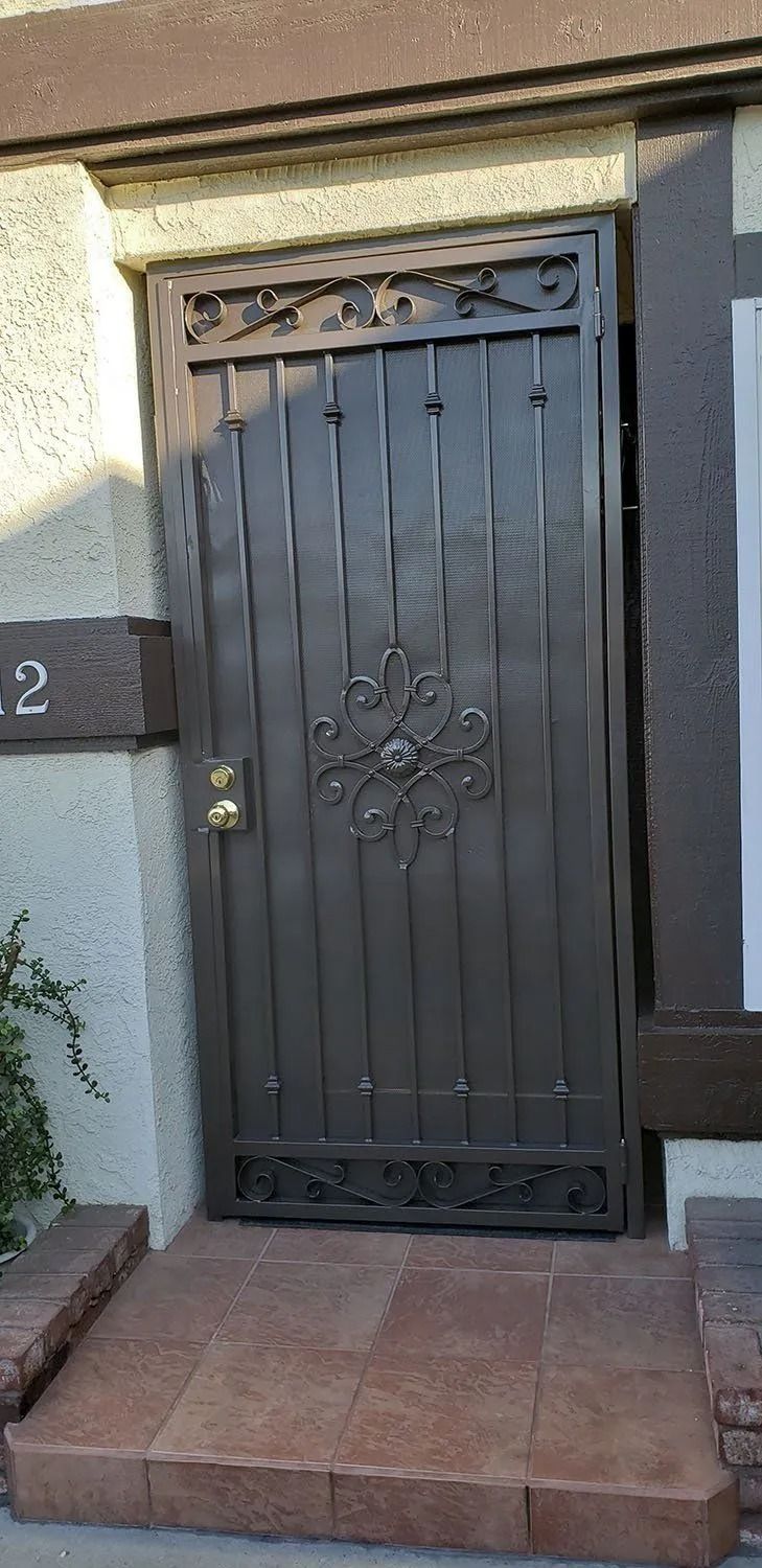 Dark metal gate with ornate details on a raised brown stone platform.