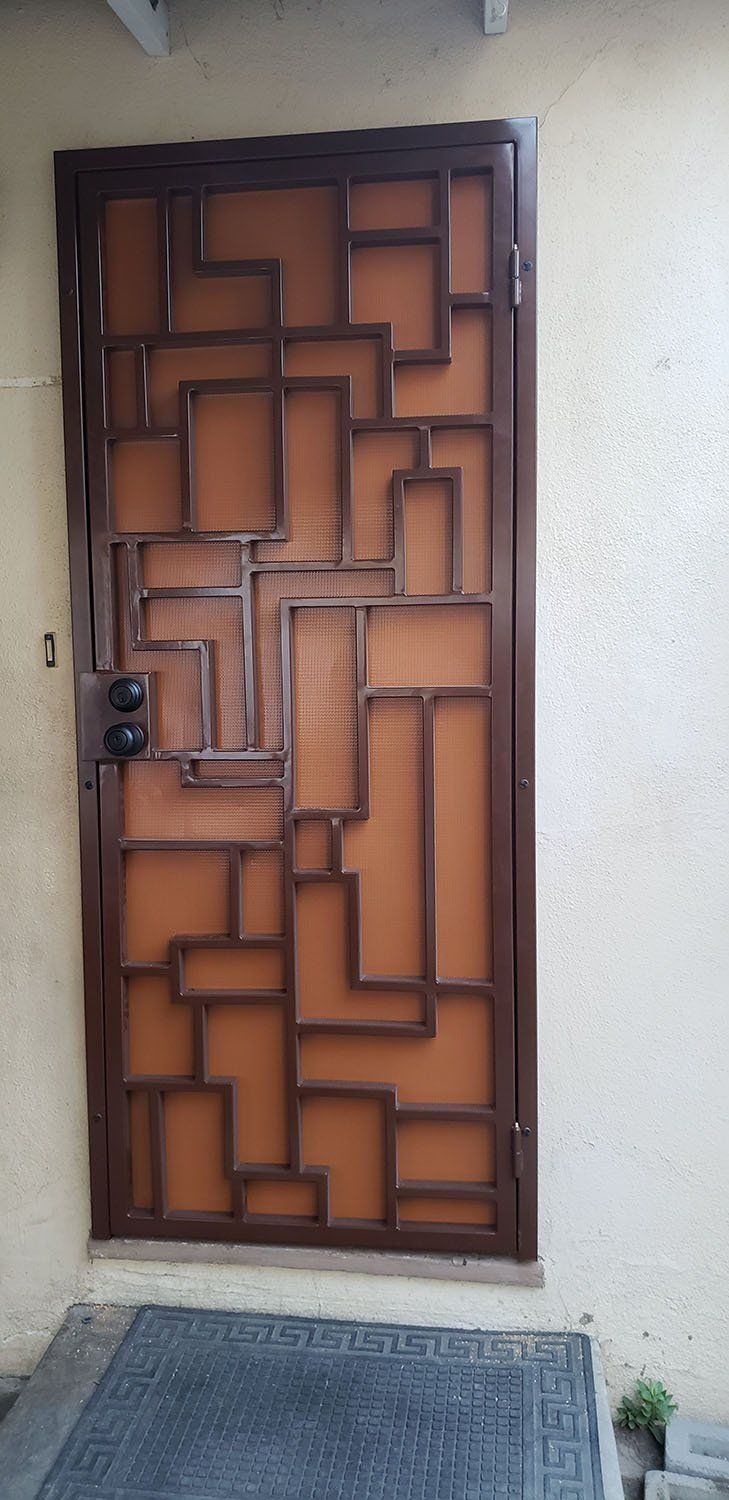 Brown metal door with geometric design, set in a light beige wall.