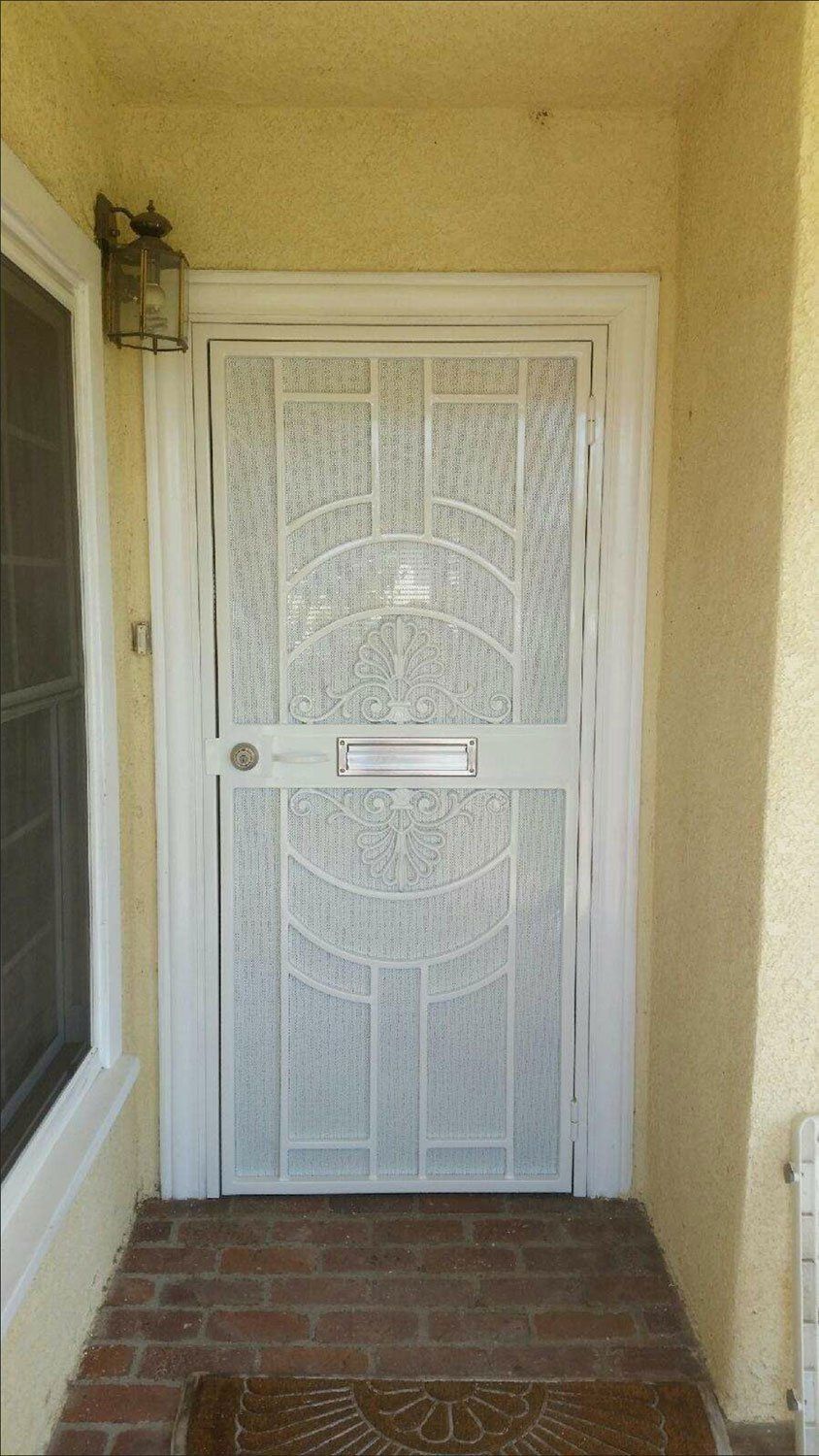 White security door with ornate metalwork on a brick porch.