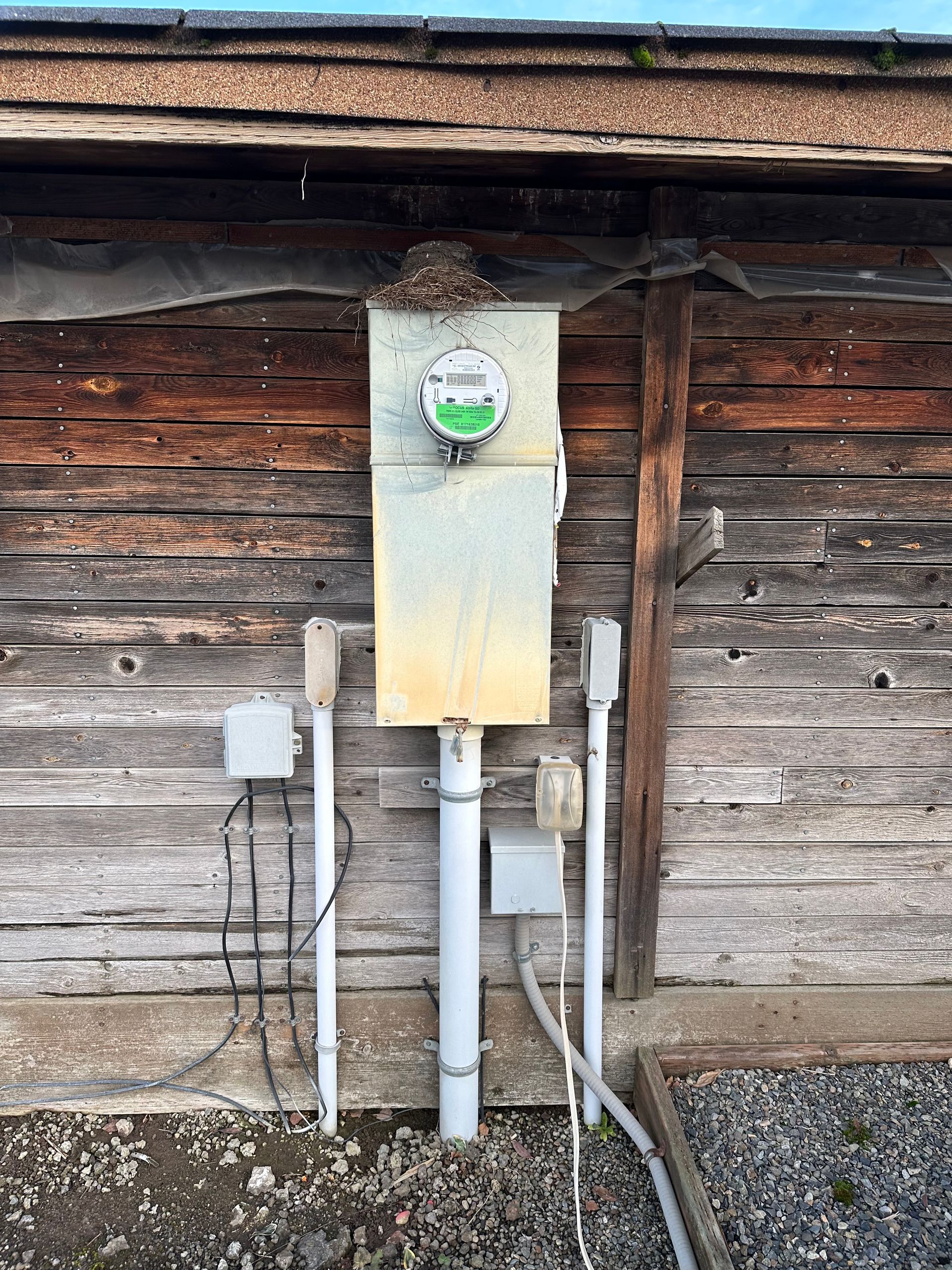 There is a meter on the side of a wooden building.