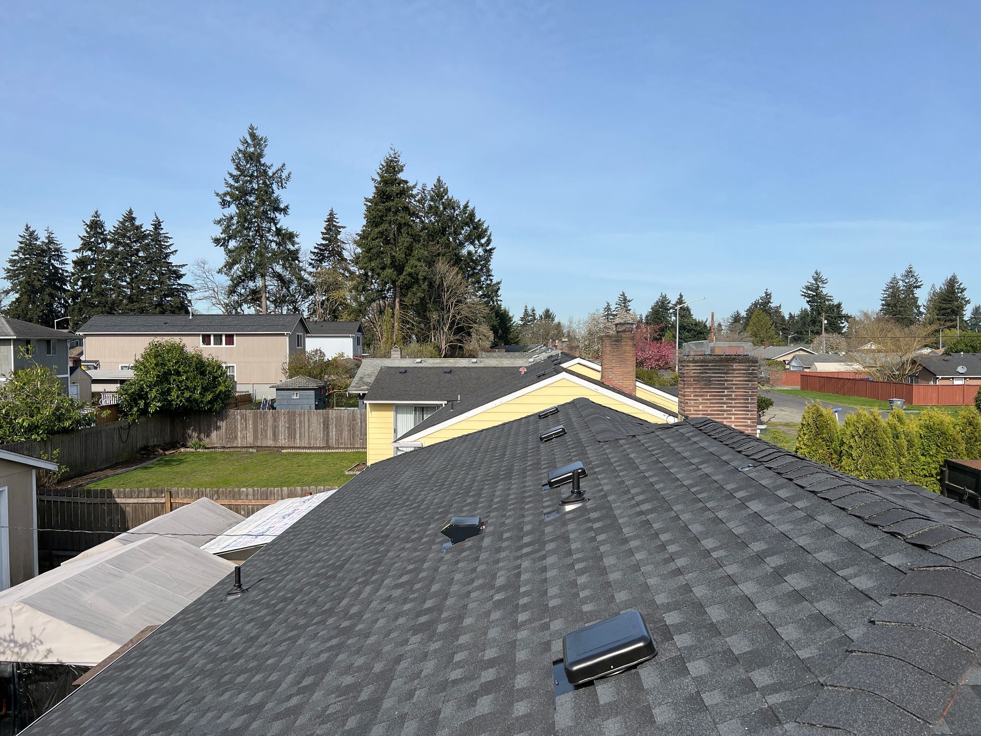 The roof of a house with a lot of windows and trees in the background