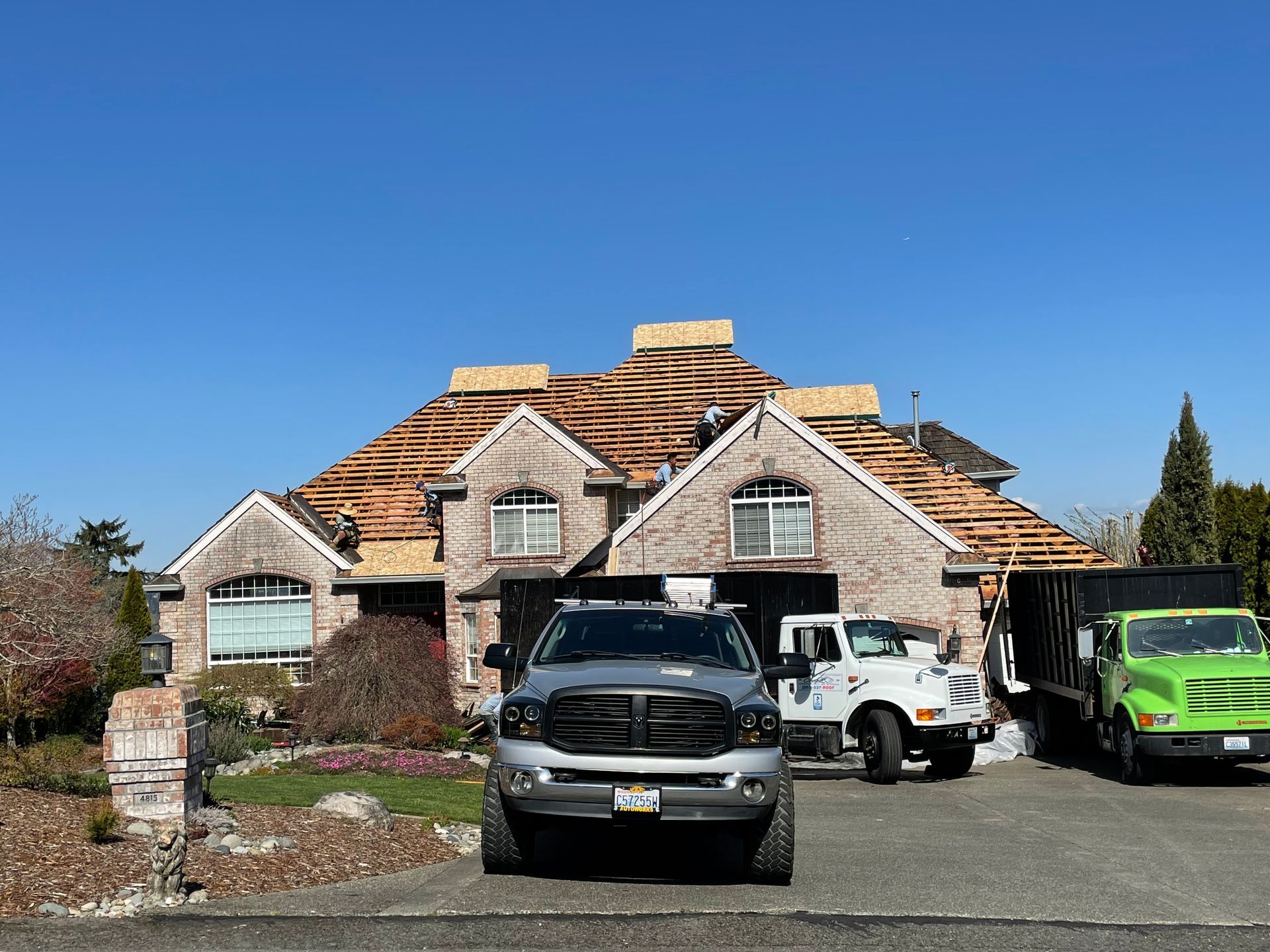 Two trucks are parked in front of a house under construction.