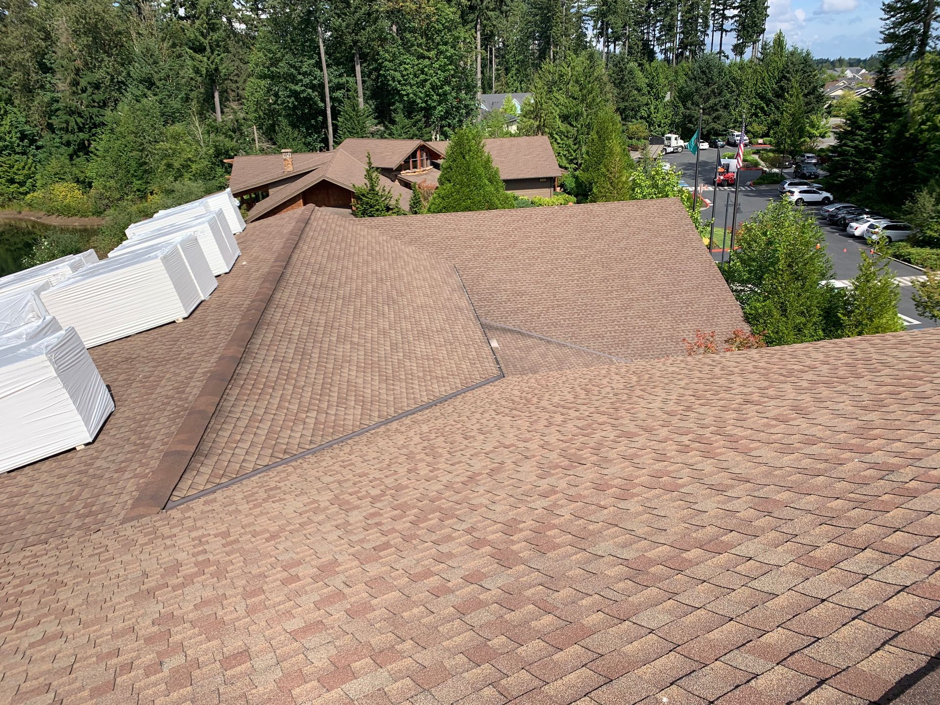 An aerial view of a brown roof with a lot of trees in the background.