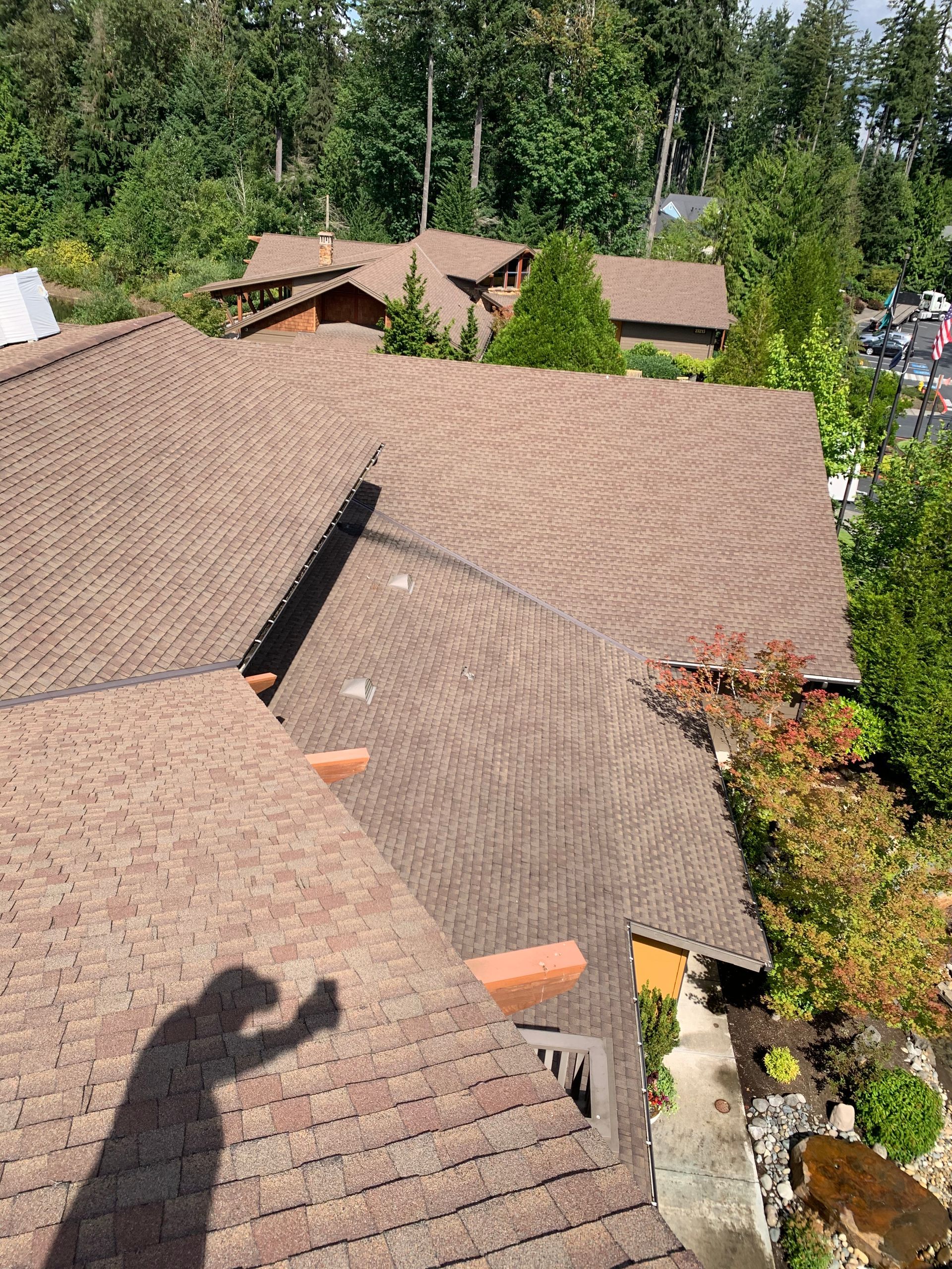 A shadow of a person is cast on the roof of a house.