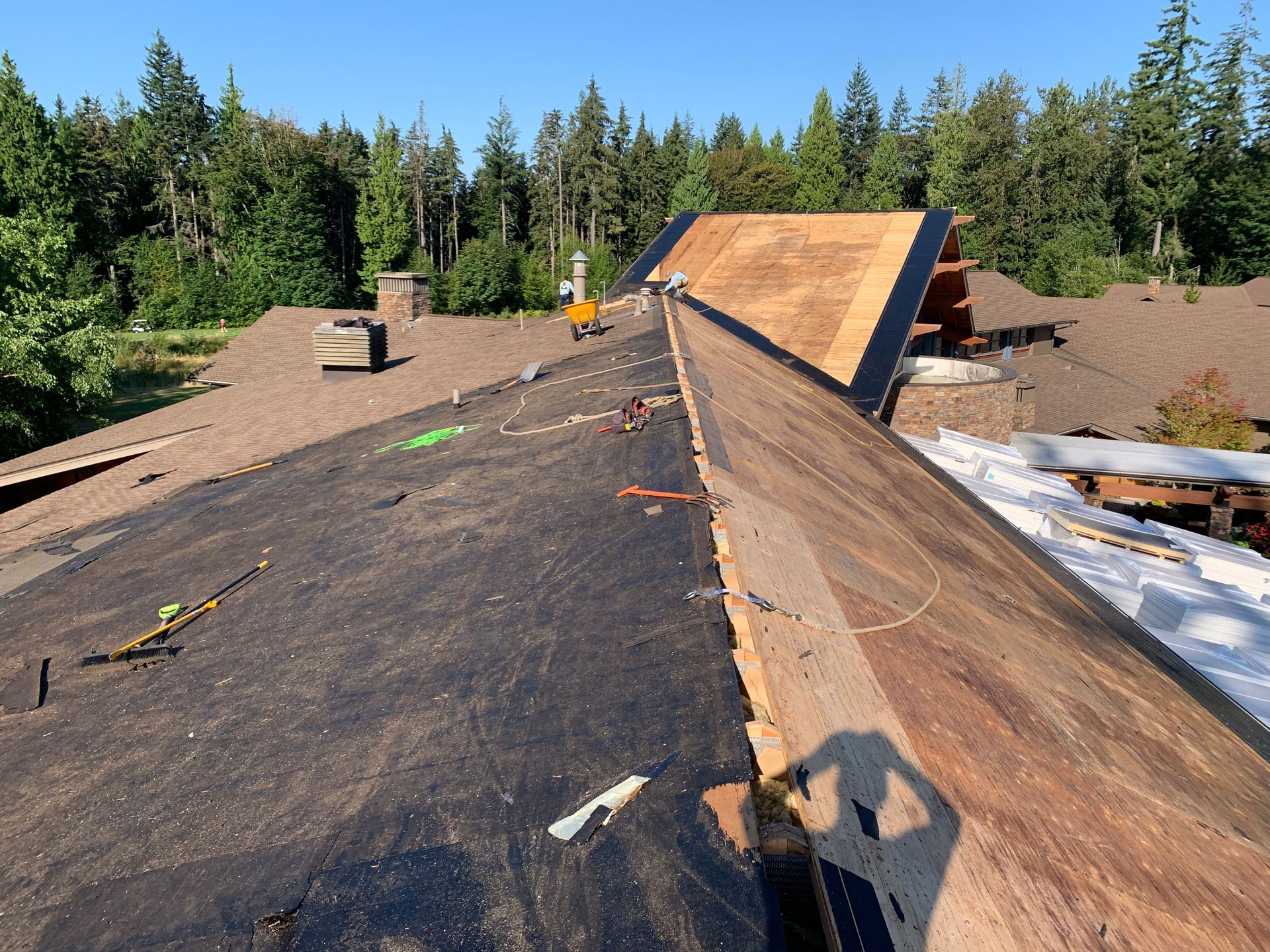 A wooden roof is being built on a sunny day with trees in the background.