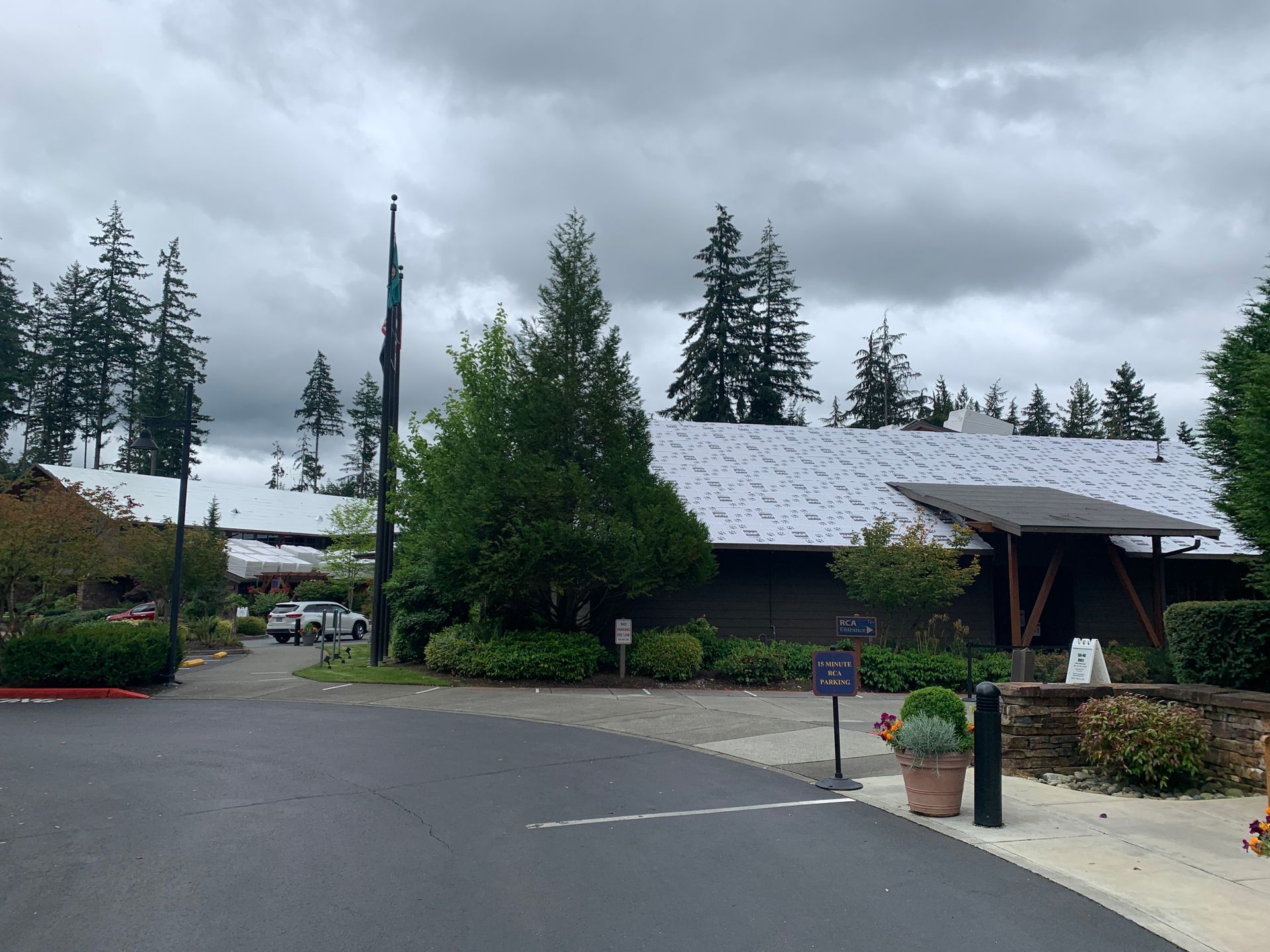 A house with a white roof is surrounded by trees on a cloudy day