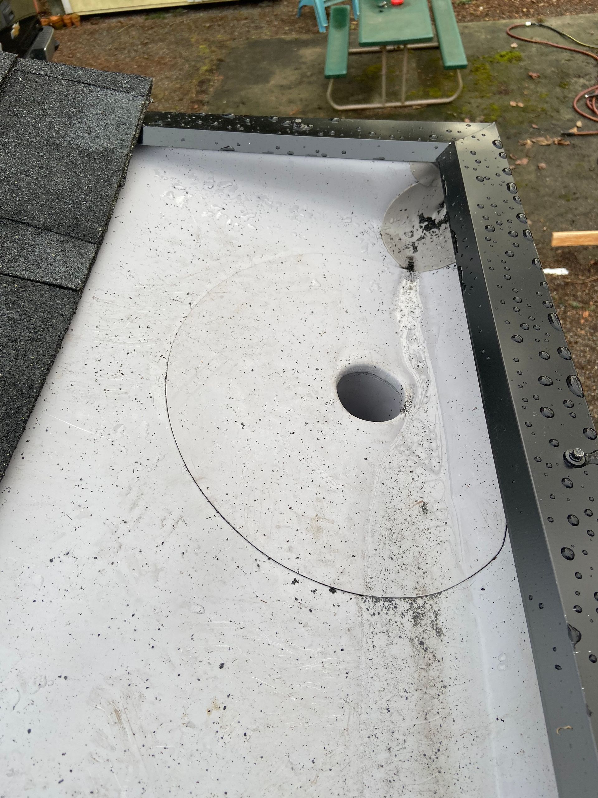 A roof with a hole in it and a picnic table in the background