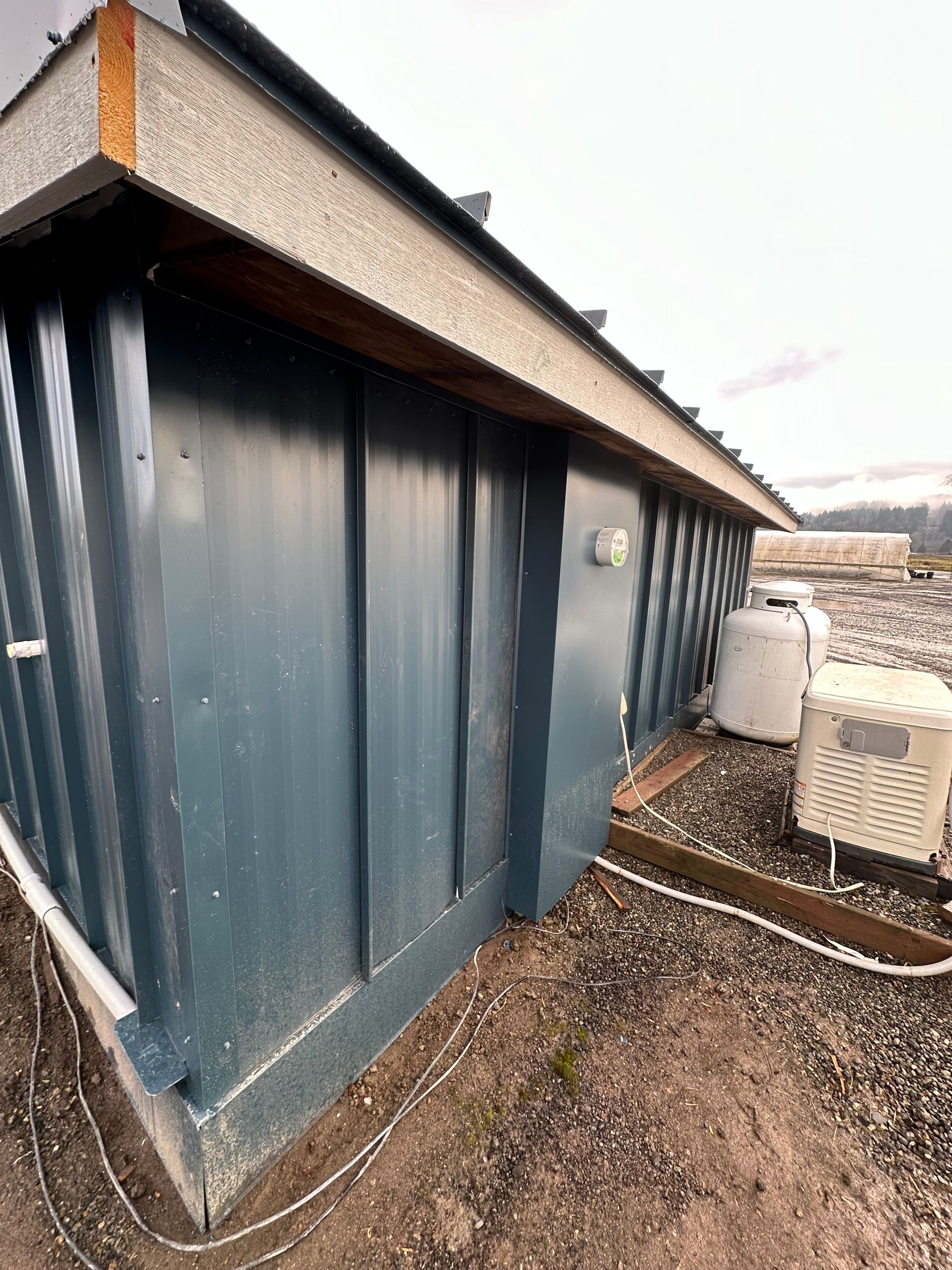 A blue building with a roof is sitting on top of a dirt field.