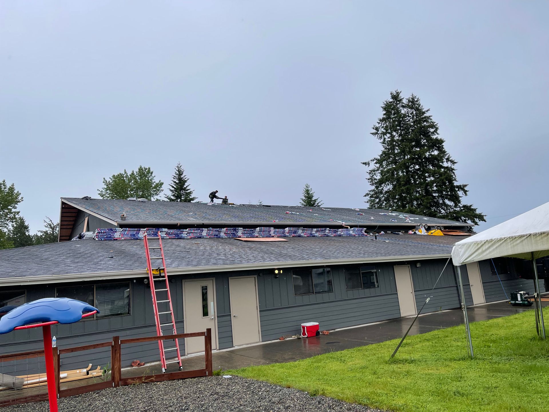 A house with a ladder on the roof is being remodeled.